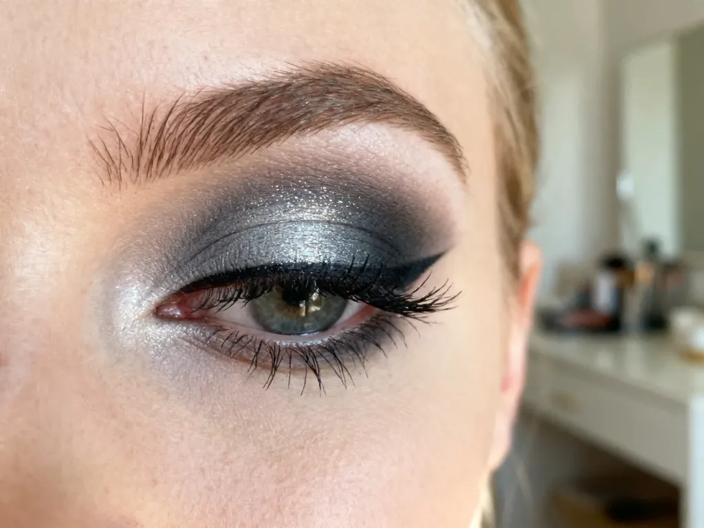 Makijaż typu smokey eye w odcieniach szarości i czerni na powiece z wyraźnie podkreślonymi rzęsami.